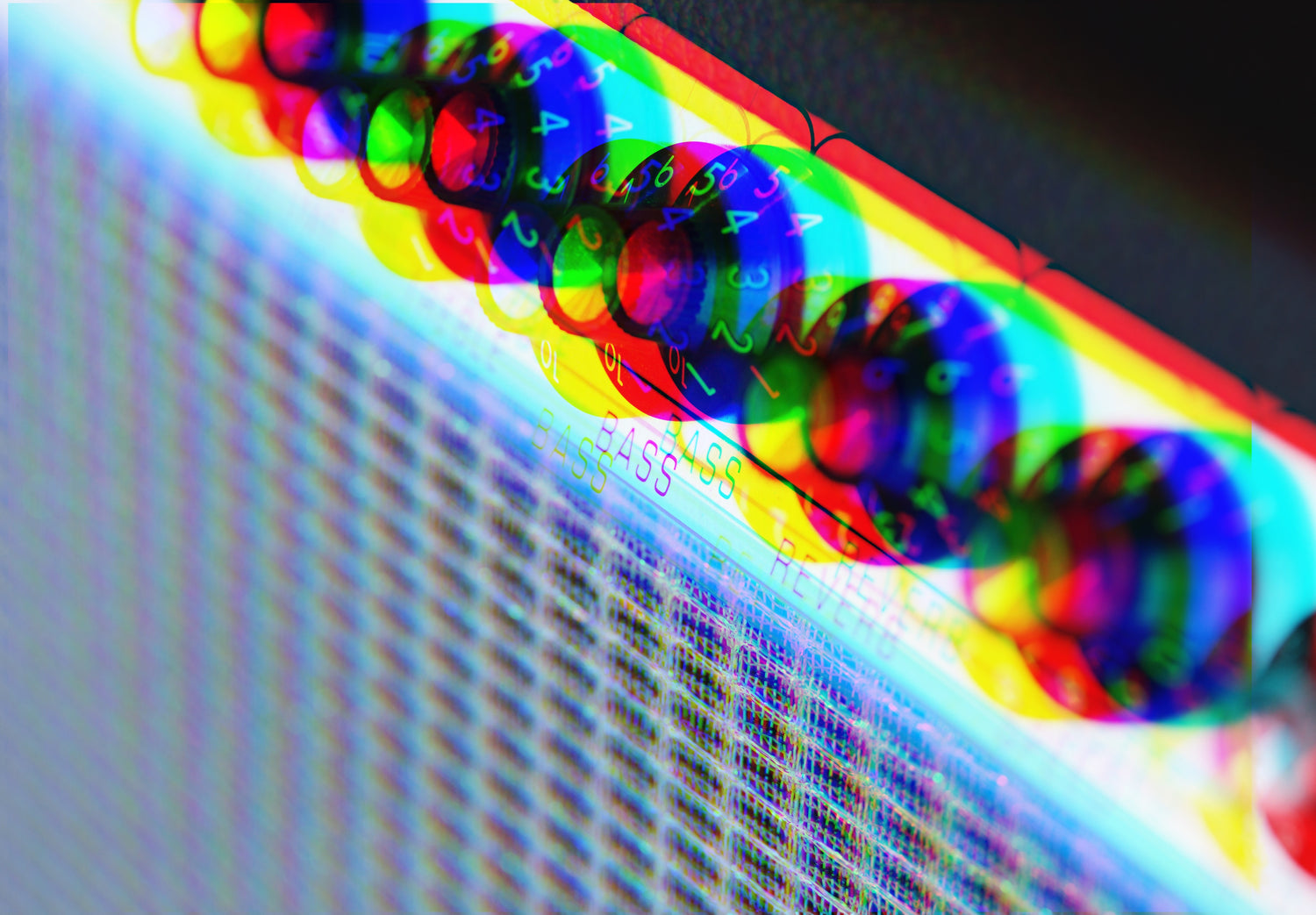 Close-up photograph of a guitar amplifier's bass and reverb knobs with heavy chromatic aberration giving it a colorful, abstract appearance.